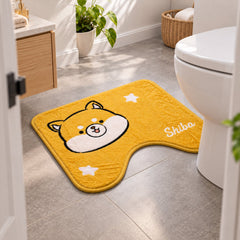 A yellow U-shaped toilet mat with a Shiba Inu design and white stars, seen from a doorway in a bathroom setting.