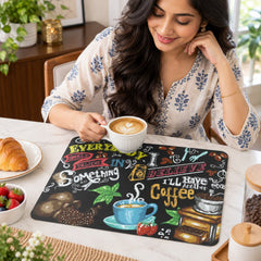 A woman smiles while holding a white coffee cup, with the coffee-themed mat on a light-colored table beside her.