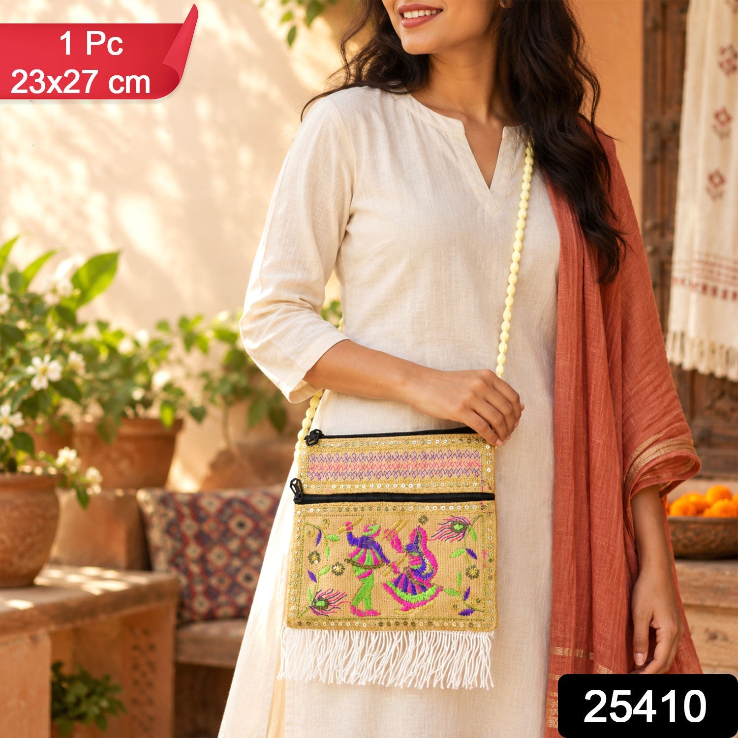 A woman wears a beige embroidered jute sling bag with a long beaded strap and white fringe. â€“ view 2