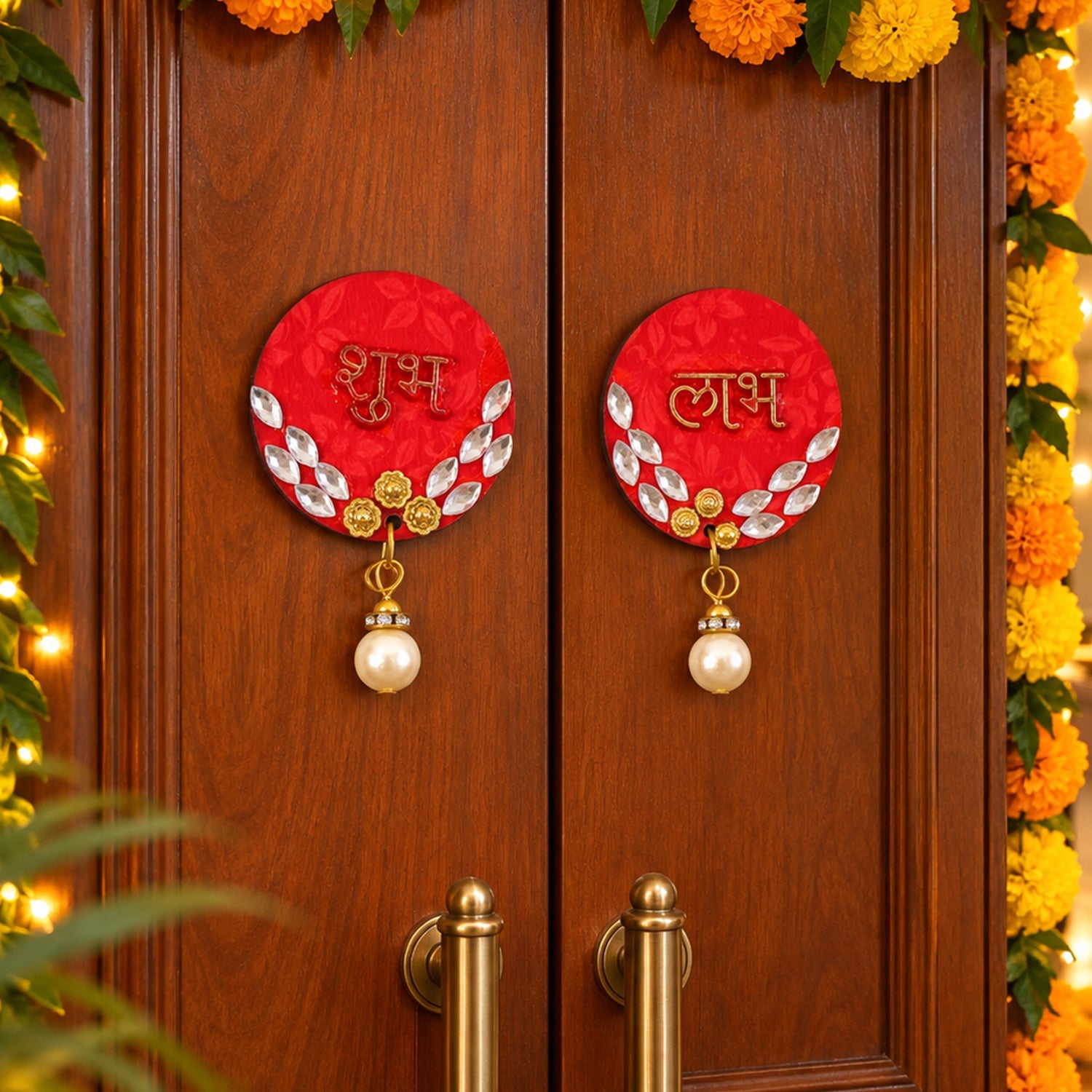 A pair of red circular Shubh Labh door decor pieces with pearl hangings adorn a wooden door, surrounded by marigold garlands.
