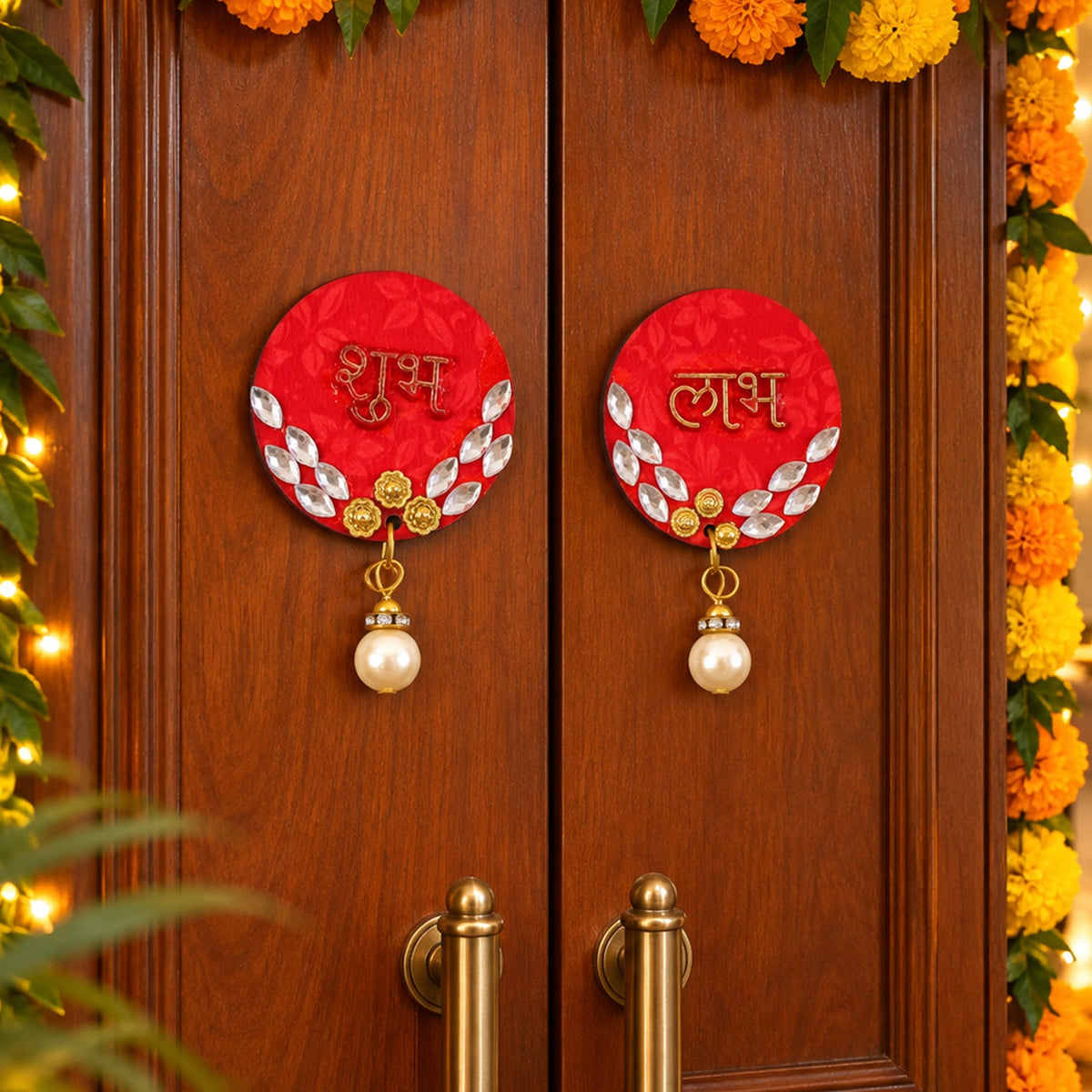 A pair of red circular Shubh Labh door decor pieces with pearl hangings adorn a wooden door, surrounded by marigold garlands.