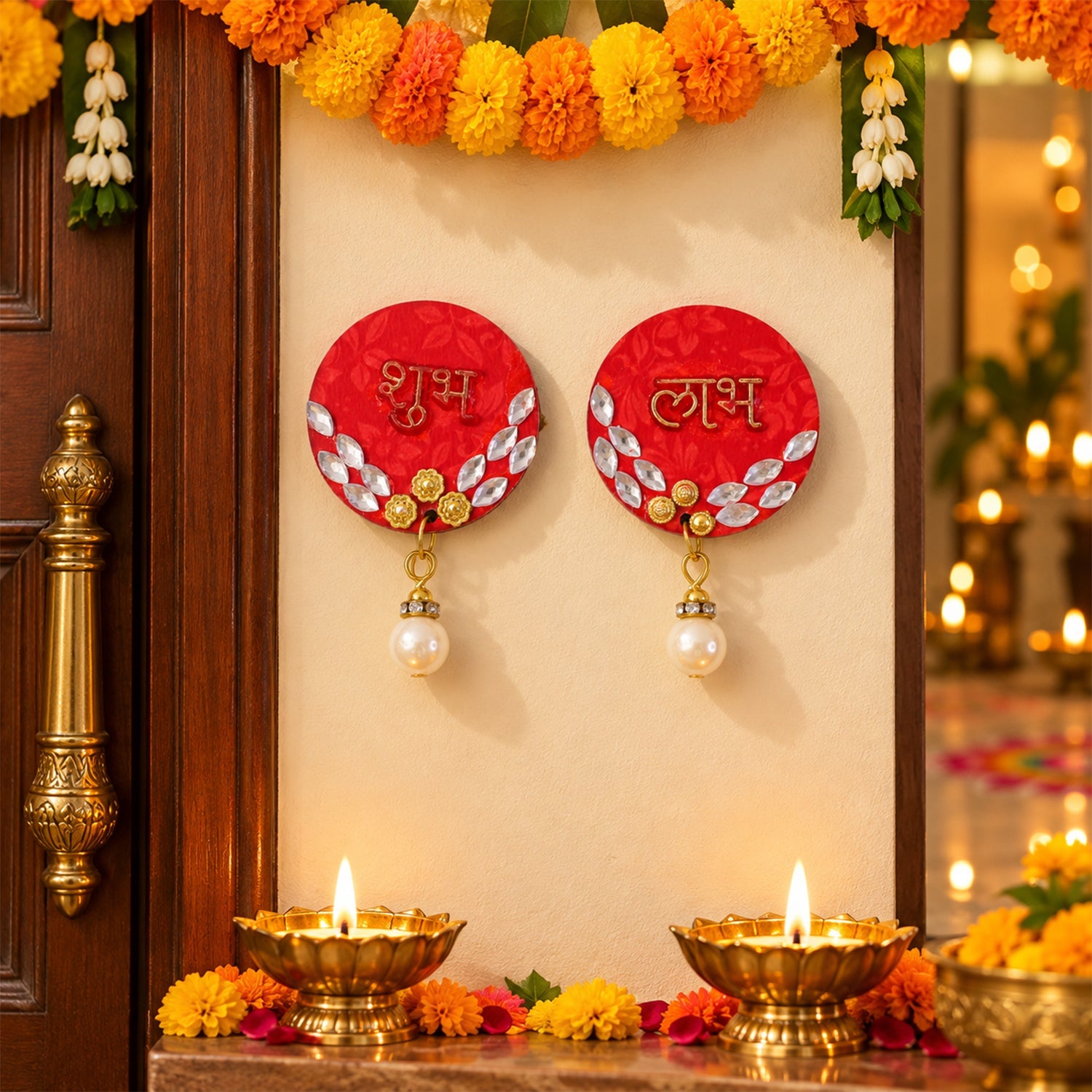 Two red circular Shubh Labh decorations with pearl hangings are affixed to a wall between two wooden doors, with lit diyas