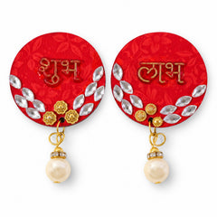 A pair of red circular Shubh Labh decorations, each featuring gold script, silver diamante accents, and a dangling pearl, on