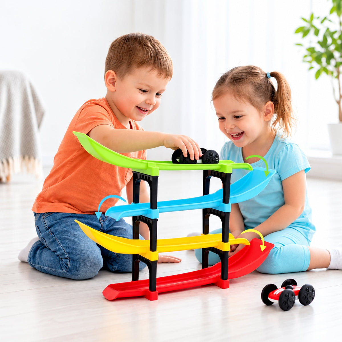Two happy children playing with a colorful four-level ramp racer toy and two small cars on a light wooden floor.