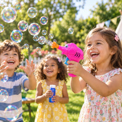Three happy children play outdoors with a pink elephant bubble gun, creating many bubbles in the sunlight.