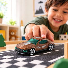 A child's hand pushes a brown toy car with green windows on a gray and white checkered road mat.