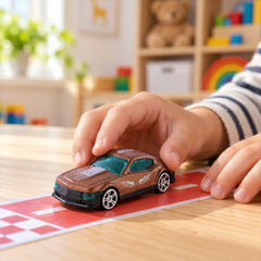 A child's hands position a small, brown toy car onto a red and white checkered track.