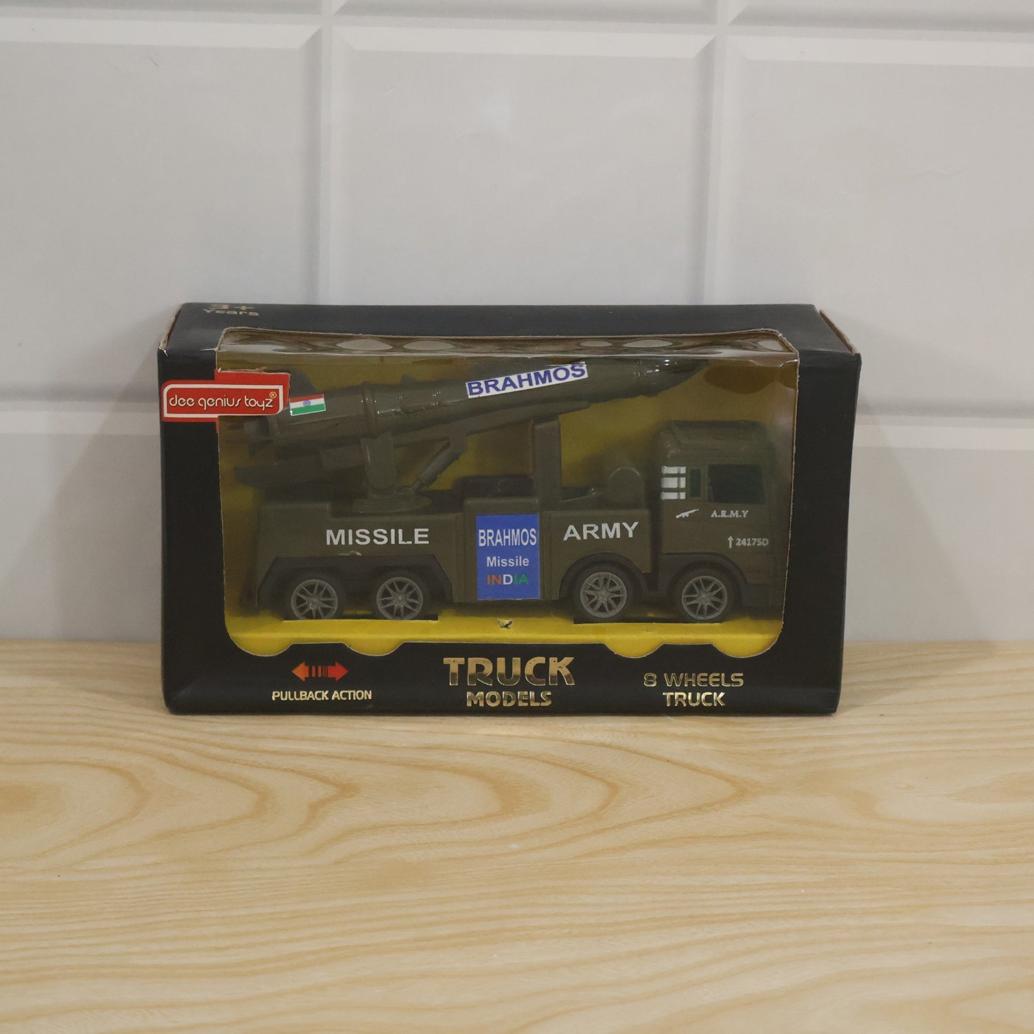 The green toy army truck with a missile launcher is displayed in its black and clear plastic packaging.