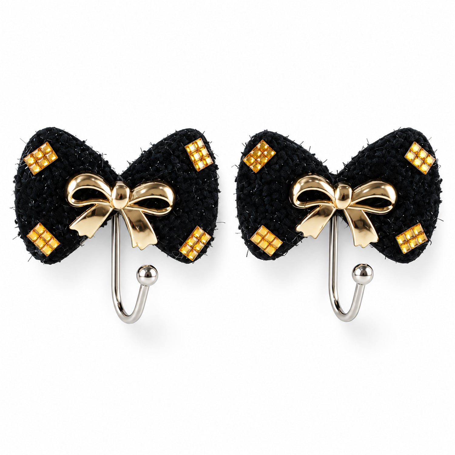 A pair of black bow-shaped hooks with gold-tone accents and a central gold bow, presented on a clean white surface.