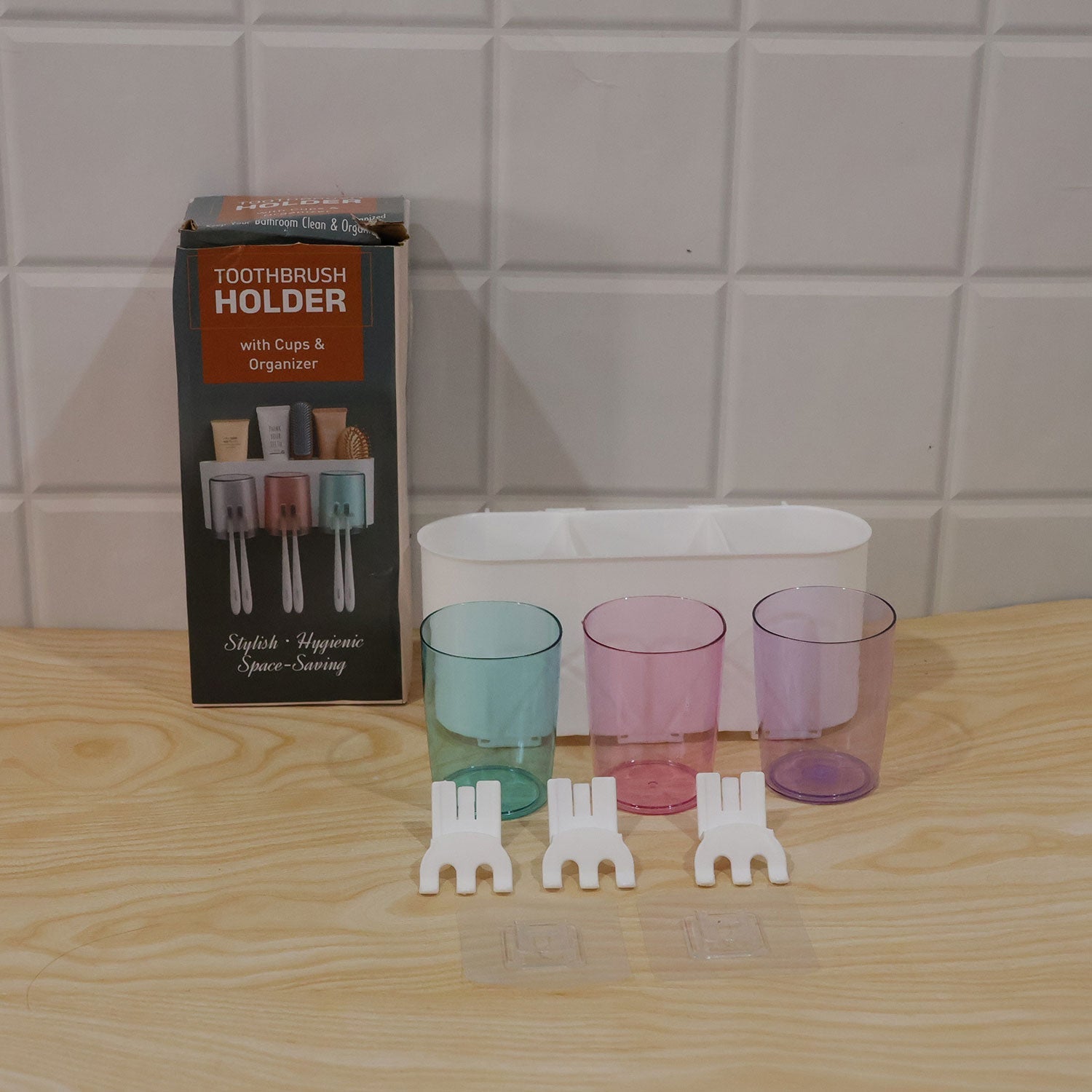 Unboxed components of a toothbrush holder set, including a white organizer, three colored cups, and three white holders,