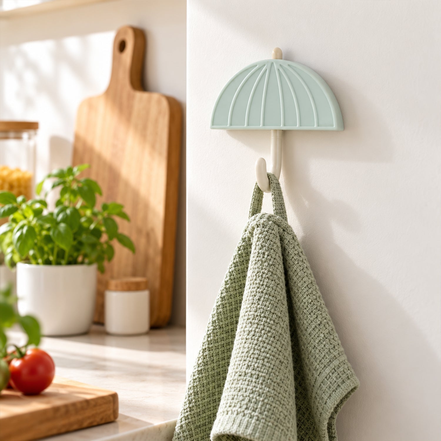 Mint green umbrella hook holding a folded light green textured towel in a kitchen setting.