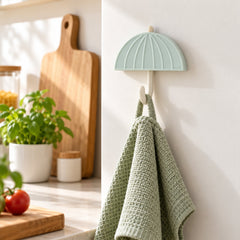 Mint green umbrella hook holding a folded light green textured towel in a kitchen setting.