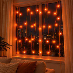A cozy living room features orange LED curtain lights on a window, casting a warm glow.