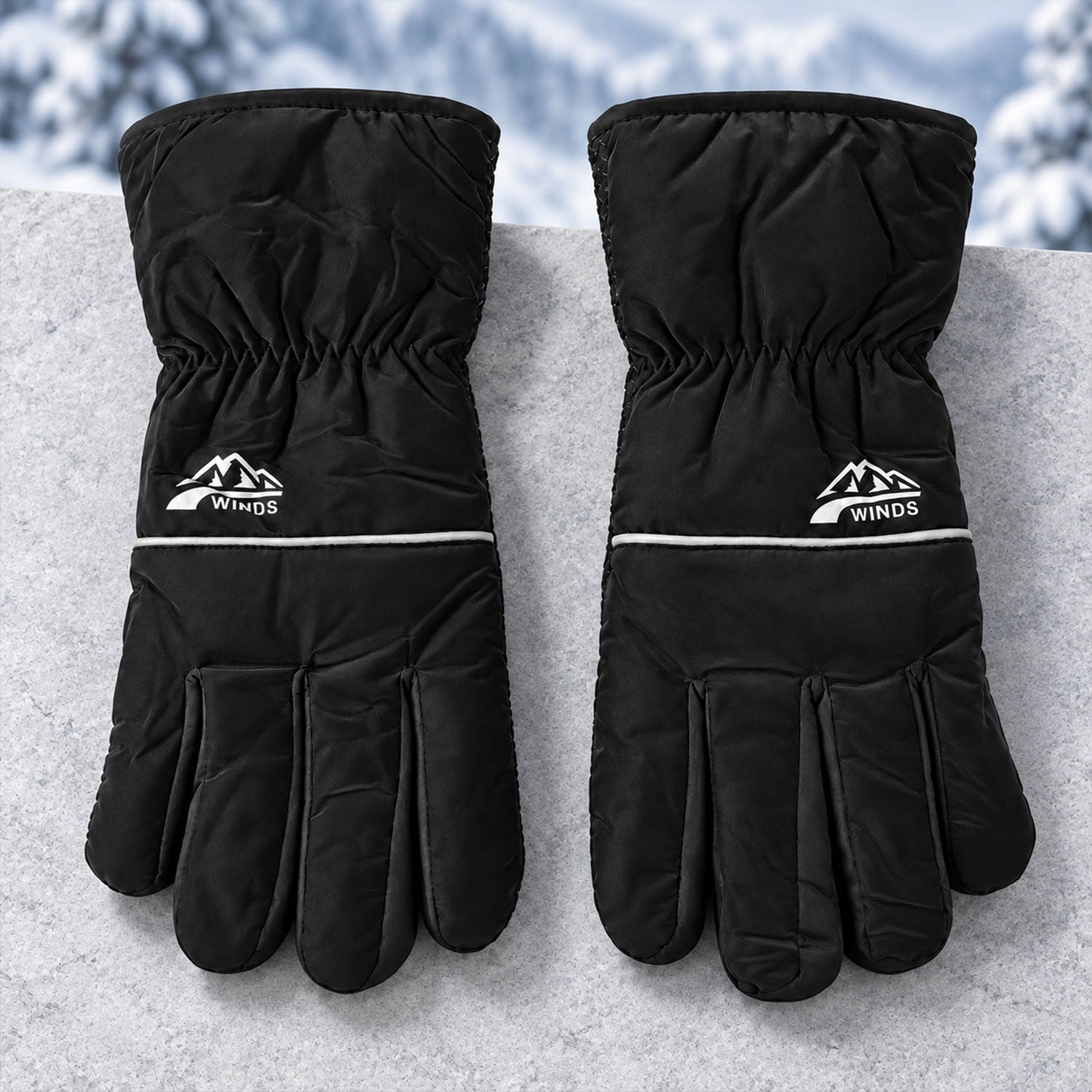 A pair of black winter gloves with white logos and reflective stripes, resting on a textured gray surface with a snowy