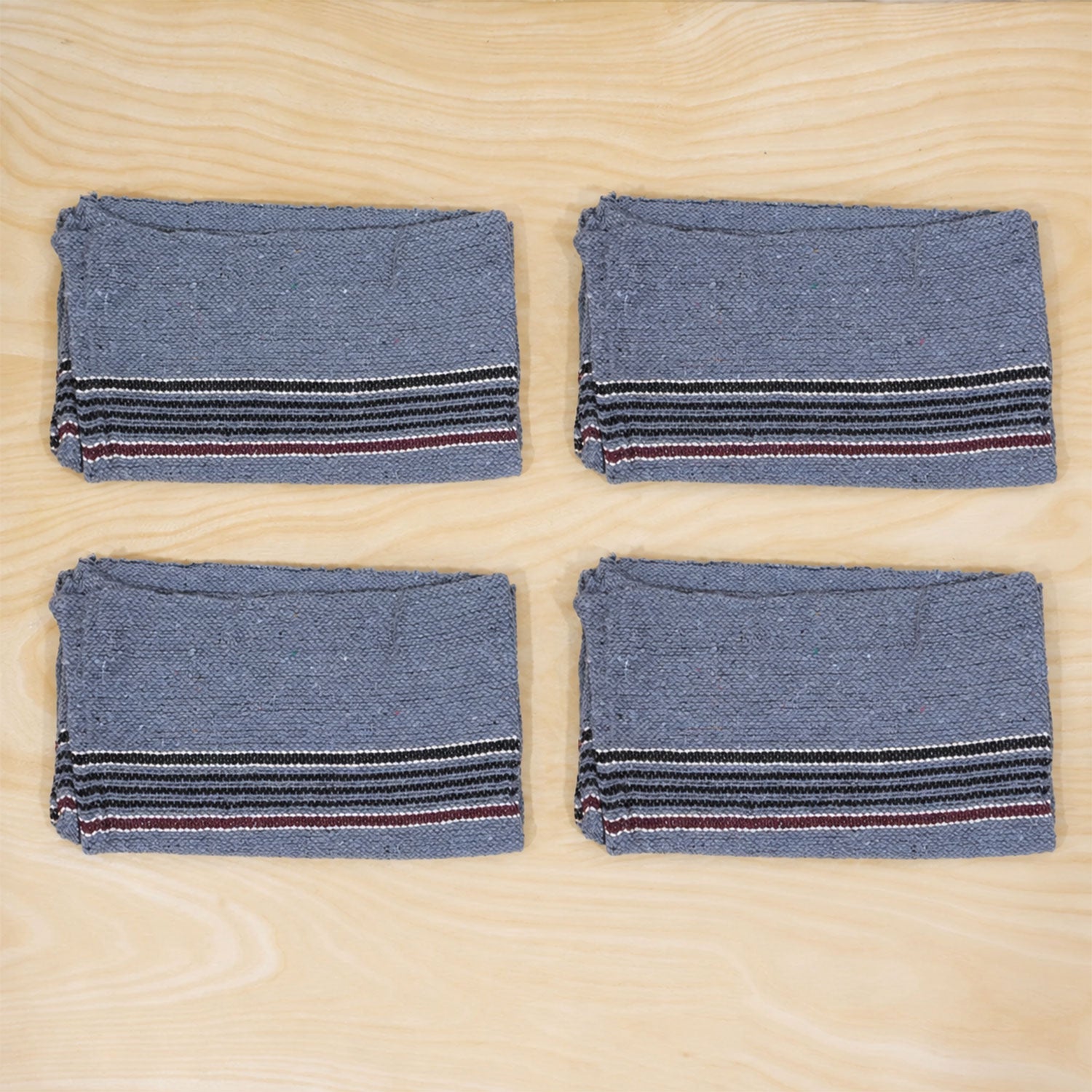 Four folded blue cleaning cloths with striped borders are neatly arranged on a wooden surface.