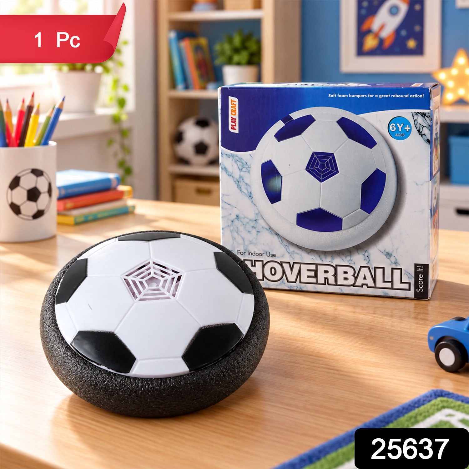 A white and black hoverball soccer toy and its product box are on a wooden desk, with a pencil holder nearby.