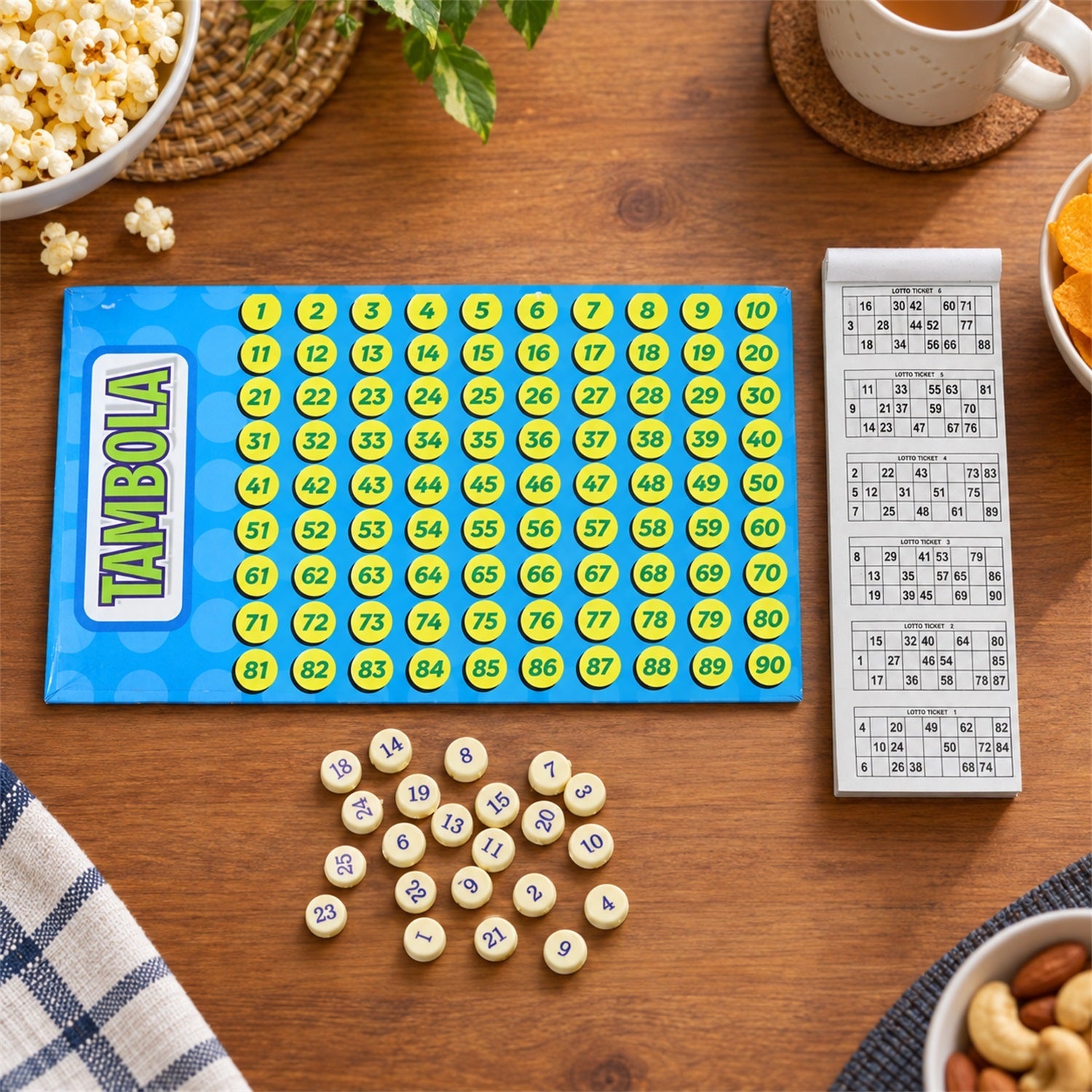 A close-up of the Tambola game board with yellow numbered circles, a ticket booklet, and loose yellow tokens on a wooden