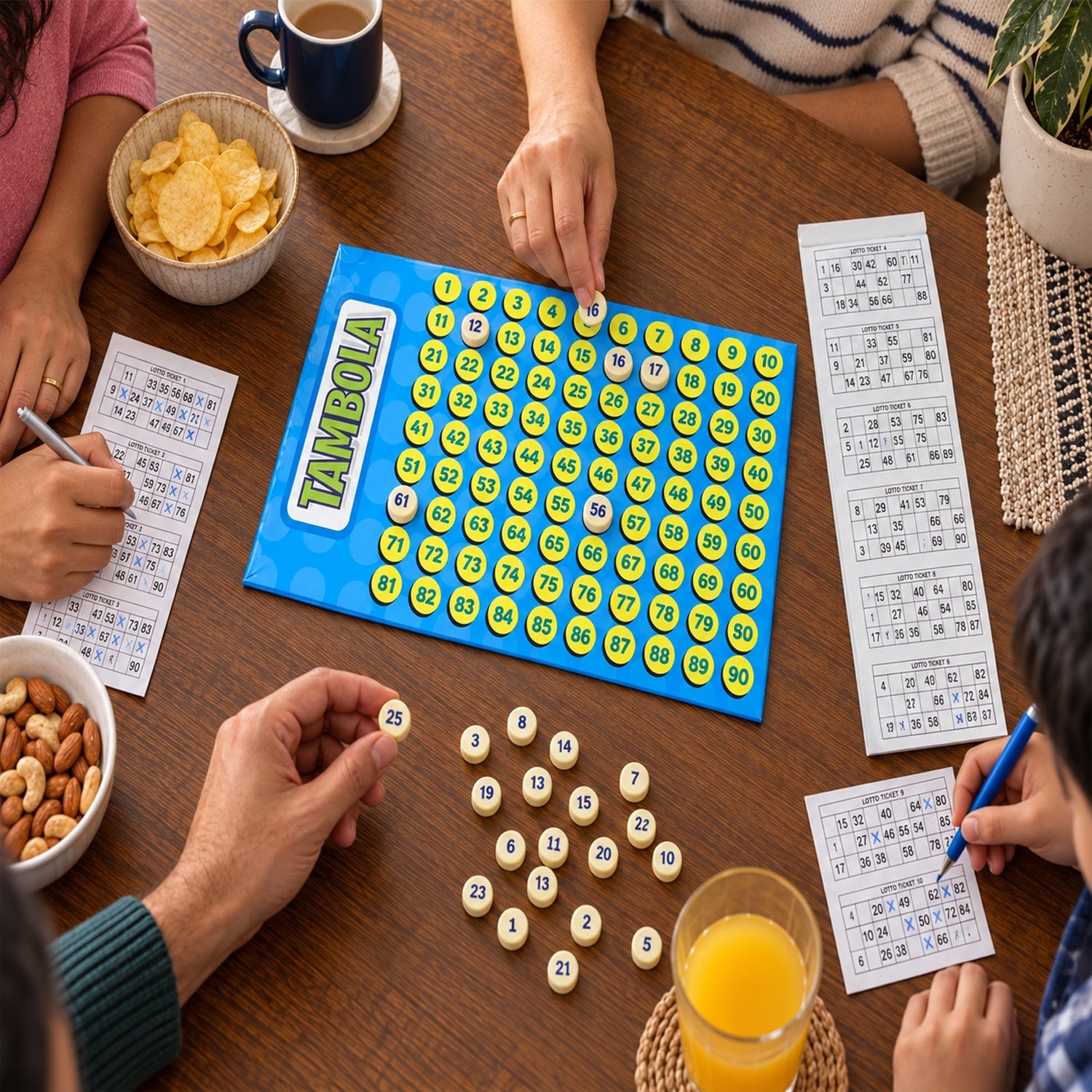Four people play Tambola at a wooden table, with hands on tickets, a blue number board, yellow tokens, and snacks visible.