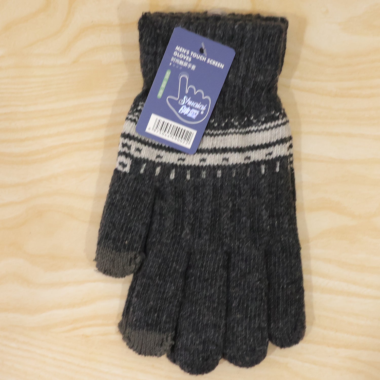 A single dark gray knitted glove with white patterned cuff and a product tag lies flat on a light wooden surface.