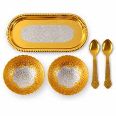 A top-down view of a golden tray, two golden bowls with silver floral patterns, and two golden spoons.
