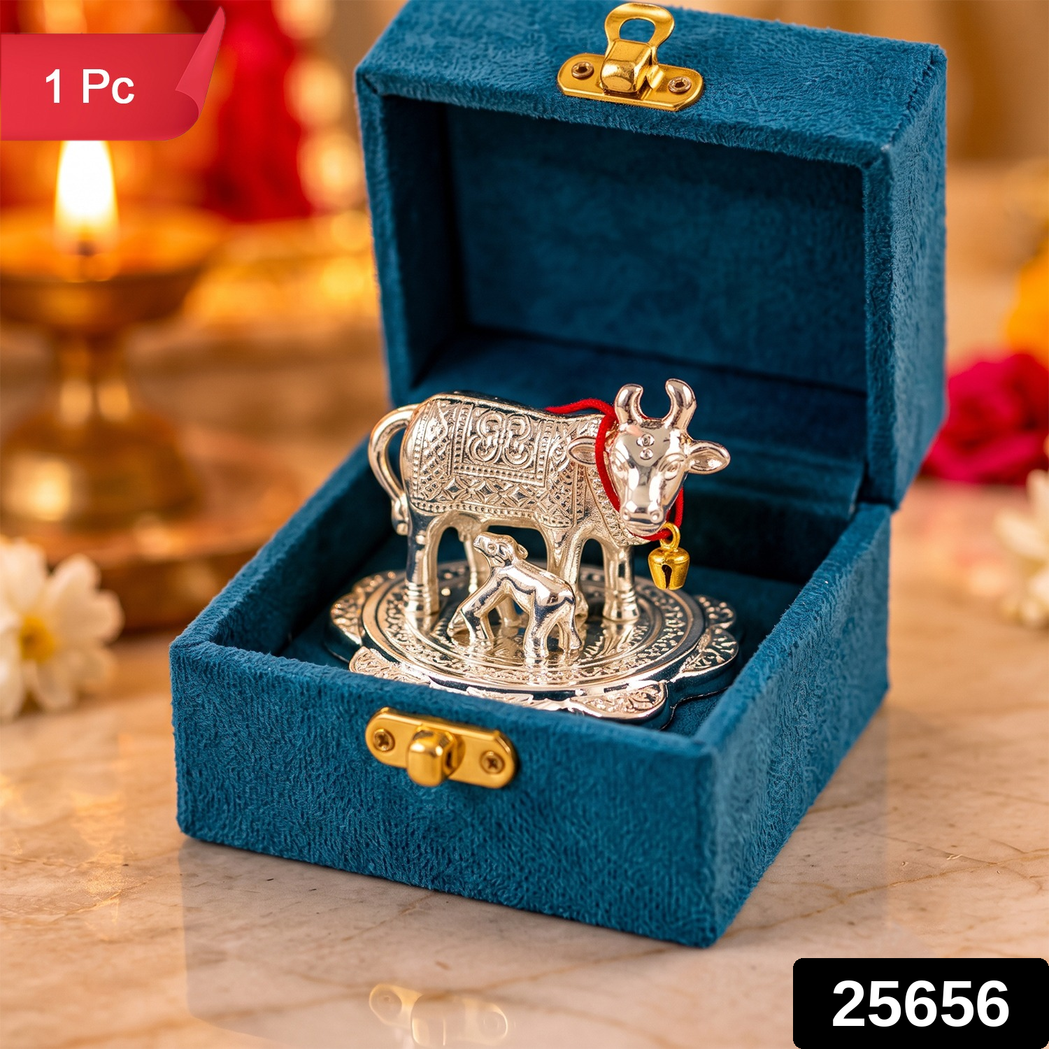 The silver cow and calf idol in the teal box, with a glowing lamp and flowers in the background.