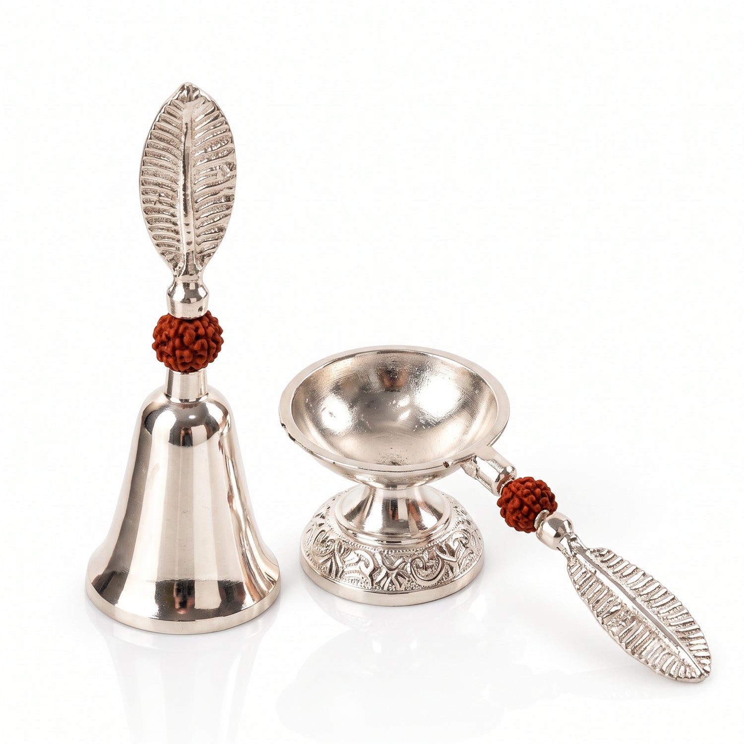 A silver finish pooja bell and diya set with leaf handles and rudraksha beads, on a clean white background.