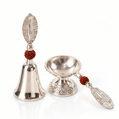 A silver finish pooja bell and diya set with leaf handles and rudraksha beads, on a clean white background.