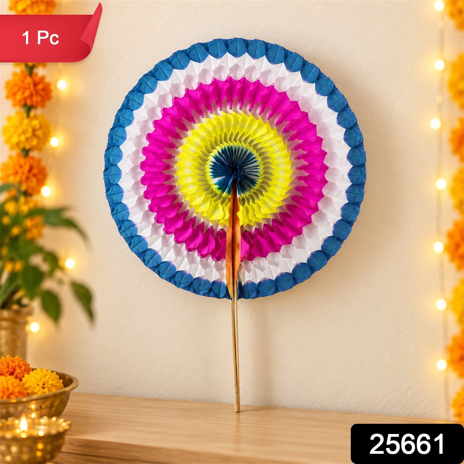 A festive paper hand fan with a circular design in blue, white, pink, yellow, and dark blue, positioned on a wooden surface