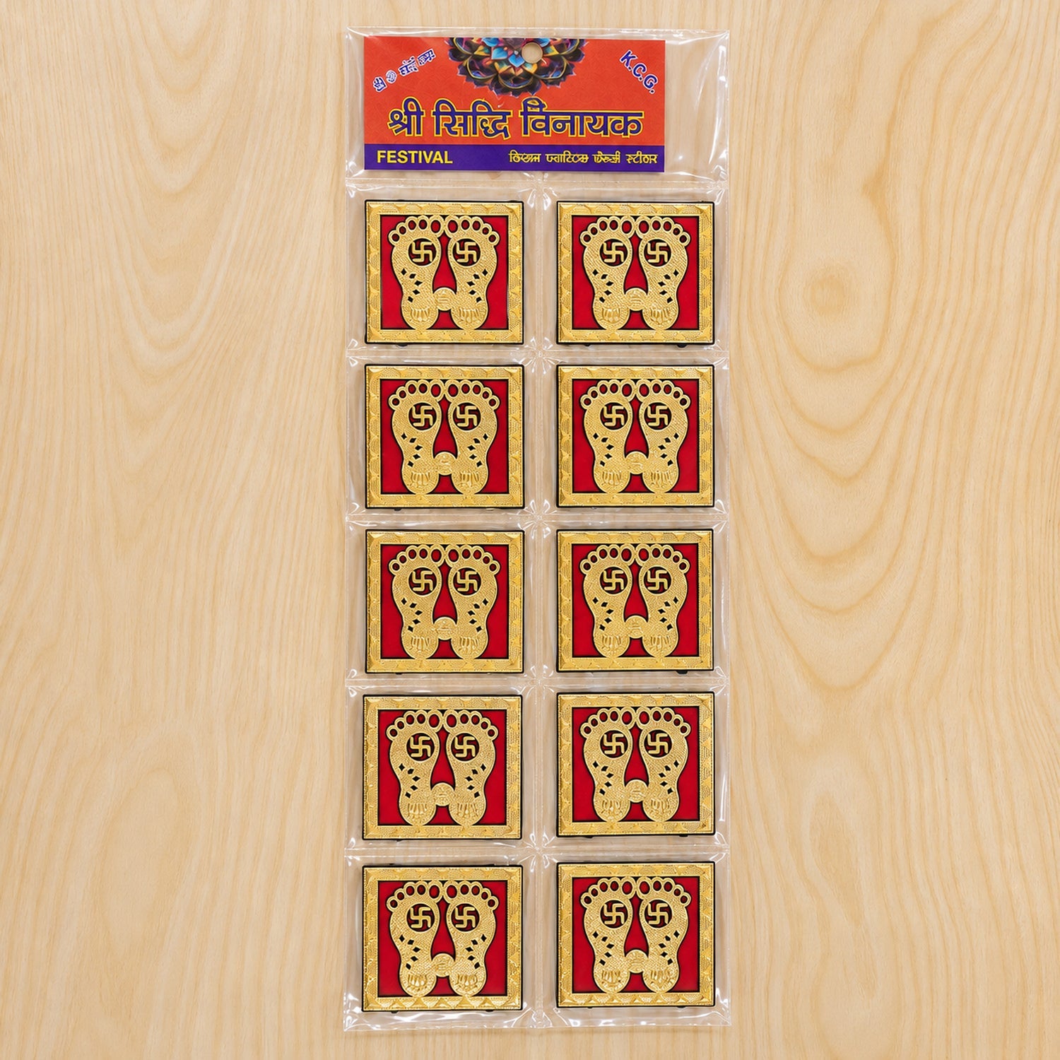 Ten golden Lakshmi Charan stickers are packaged in clear plastic, arranged vertically on a light wooden surface, with a