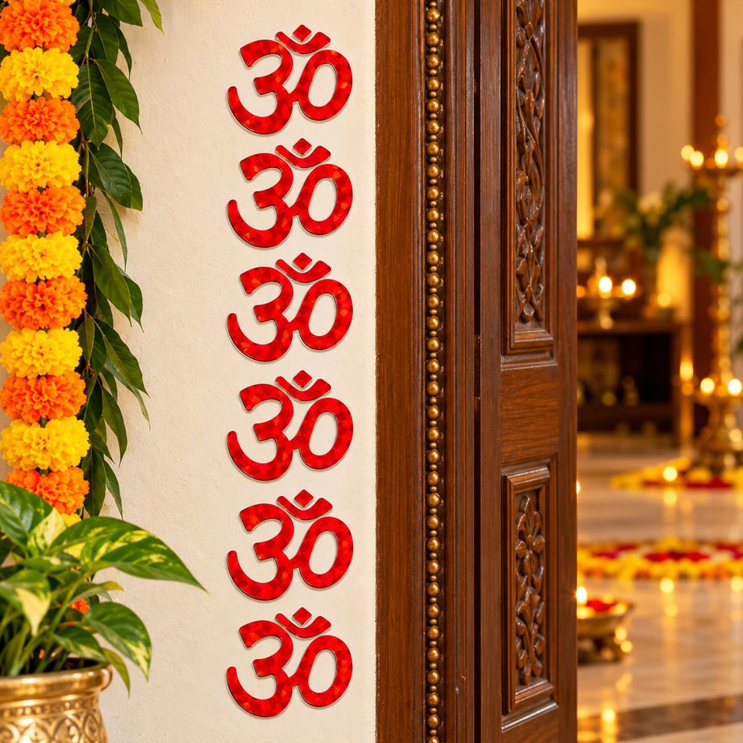 Seven red Om symbol stickers vertically decorate a wall next to a dark wooden door, with marigold garlands.