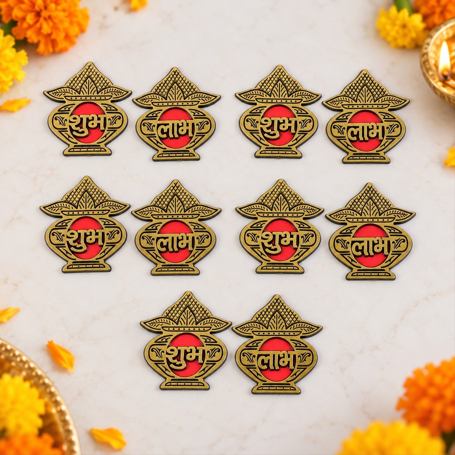 Ten golden Shubh Labh stickers are arranged on a white surface, surrounded by scattered marigold petals.