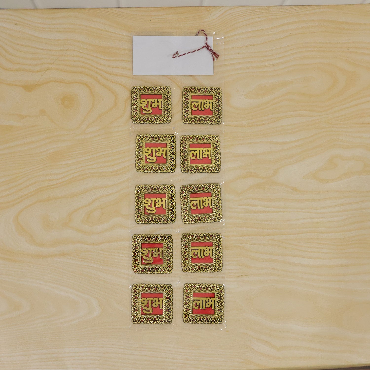Ten individual Shubh Labh stickers, arranged in five pairs, sealed in plastic packaging on a light wooden surface.
