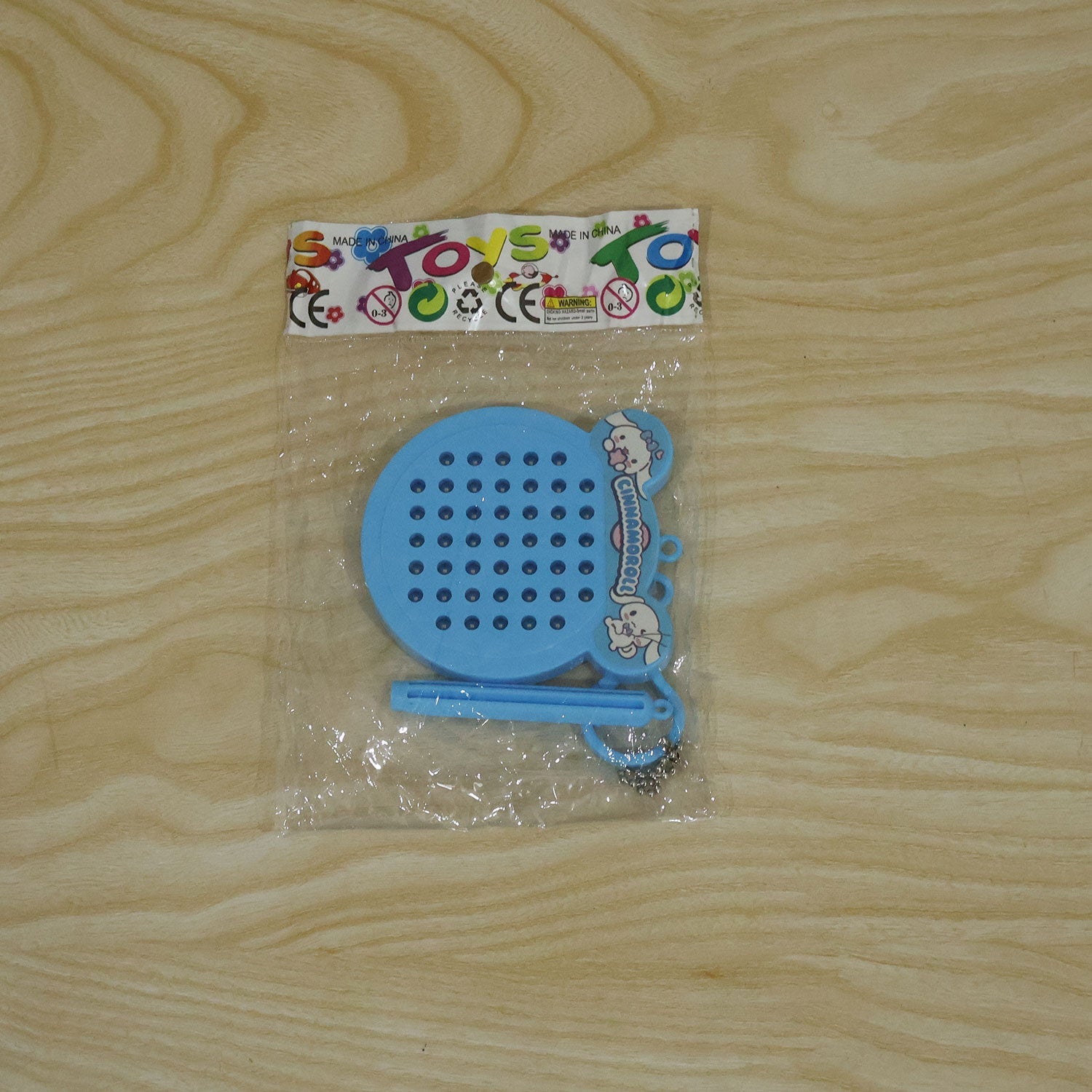 A blue Cinnamoroll magnetic drawing pad keychain with a stylus is packaged in clear plastic on a wooden surface.
