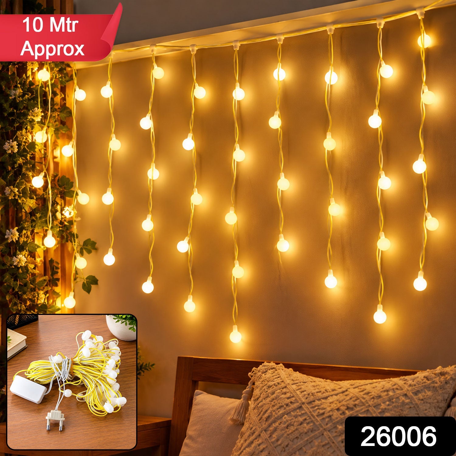 Warm white bulb string lights hang vertically on a wall above a bed with a decorative pillow and a small plant, with a