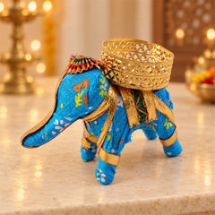 A blue fabric elephant candle holder with a gold lattice cup, viewed from a slightly elevated angle.