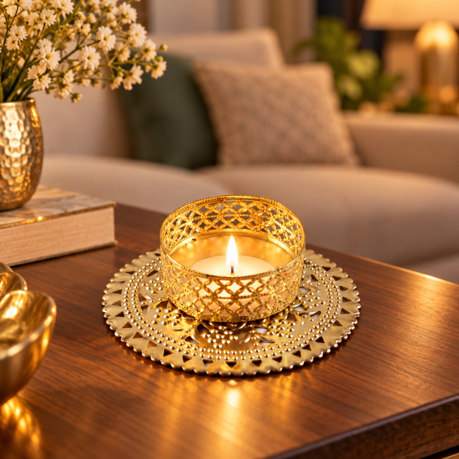 Gold tone metal jali tealight holder as part of a decorative tabletop arrangement