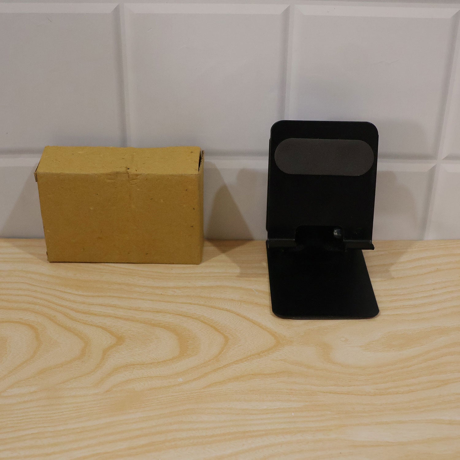 Foldable metal mobile phone stand on a desk with a laptop