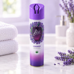 A purple and white lavender room freshener spray can stands on a white marble counter with folded towels.