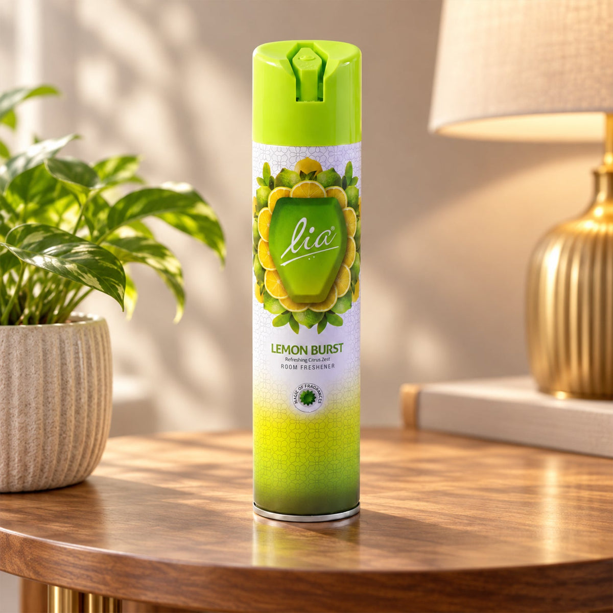 A green and white Lia Lemon Burst room freshener spray bottle stands on a wooden table beside a potted plant and a golden
