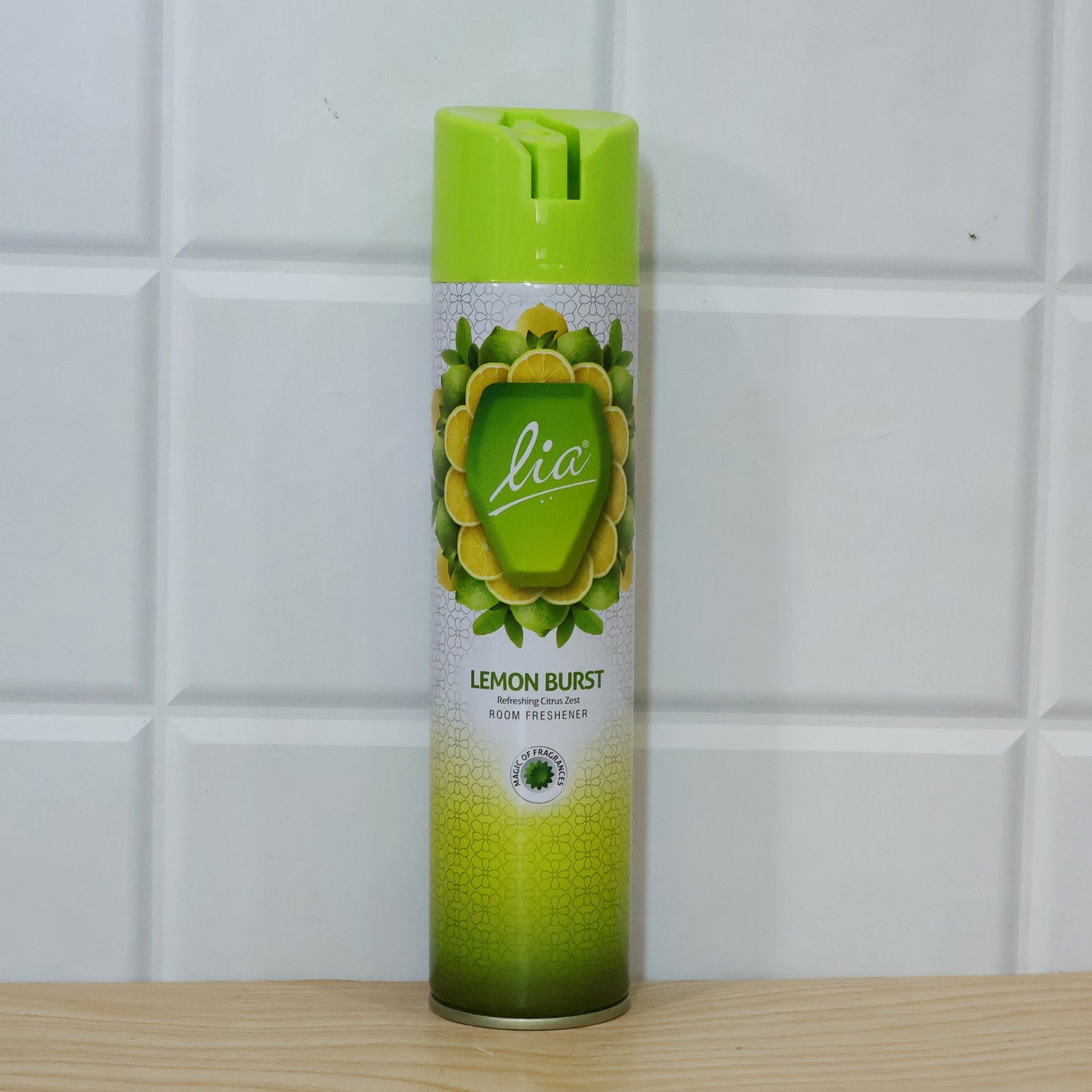 A Lia Lemon Burst room freshener bottle stands on a light wooden surface in front of a white tiled wall.