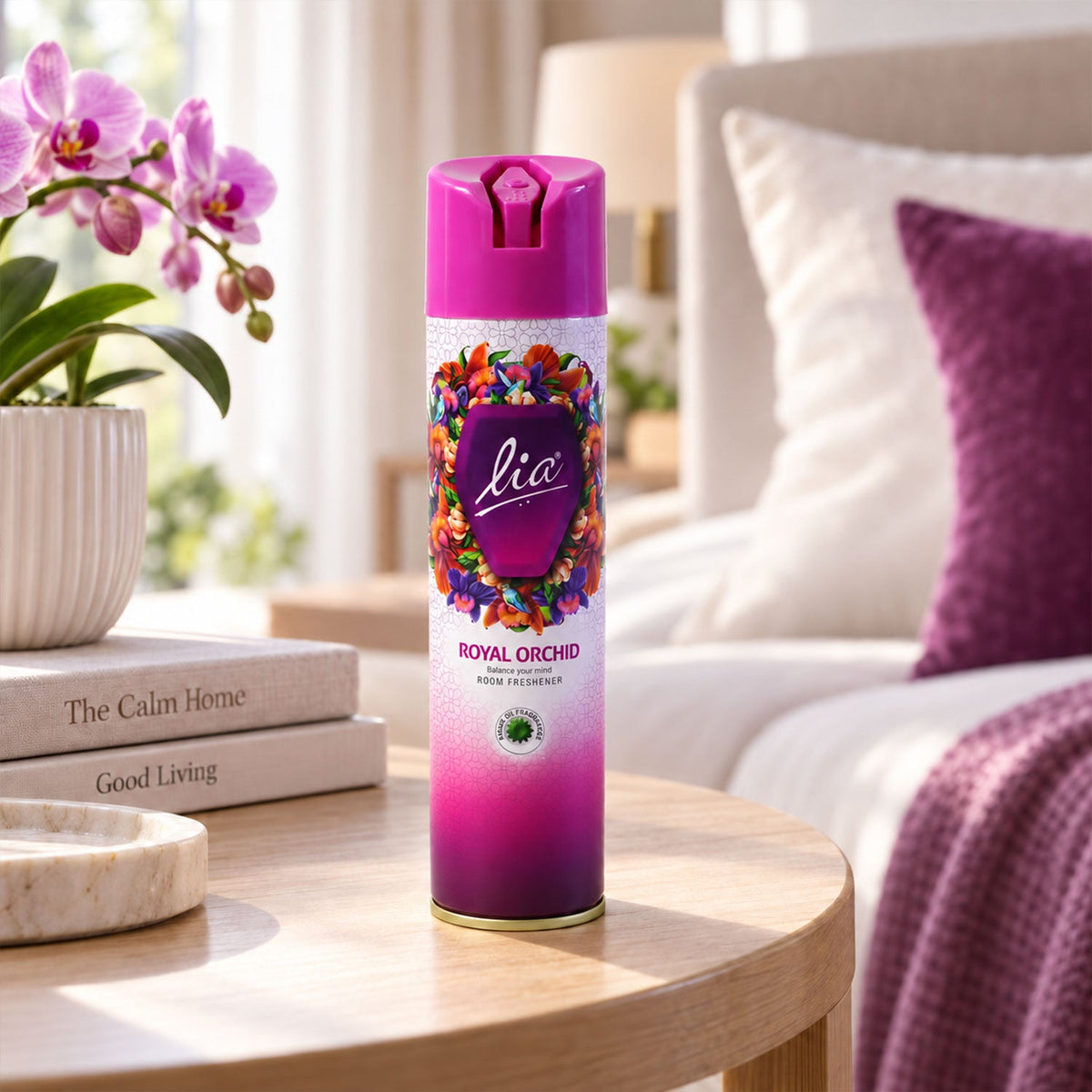 A vibrant purple and pink aerosol can with a floral design sits on a wooden table in a bright room.
