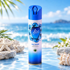 A blue and white aerosol spray can with a seashell design stands on a reflective surface by the ocean.