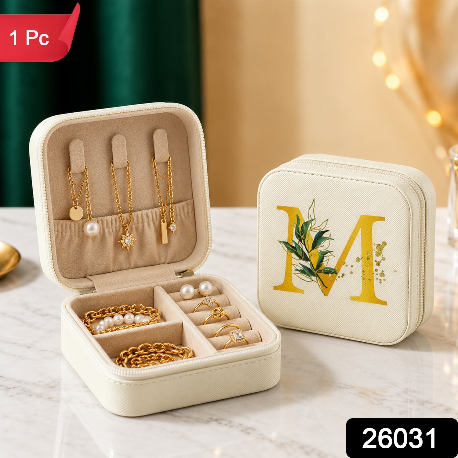 Two beige jewellery boxes, one open with accessories and one closed with a gold 'M', are displayed on a marble surface.