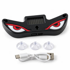 Black evil eye light with red and white eyes, a solar panel, three suction cups, and a white USB-C charging cable.
