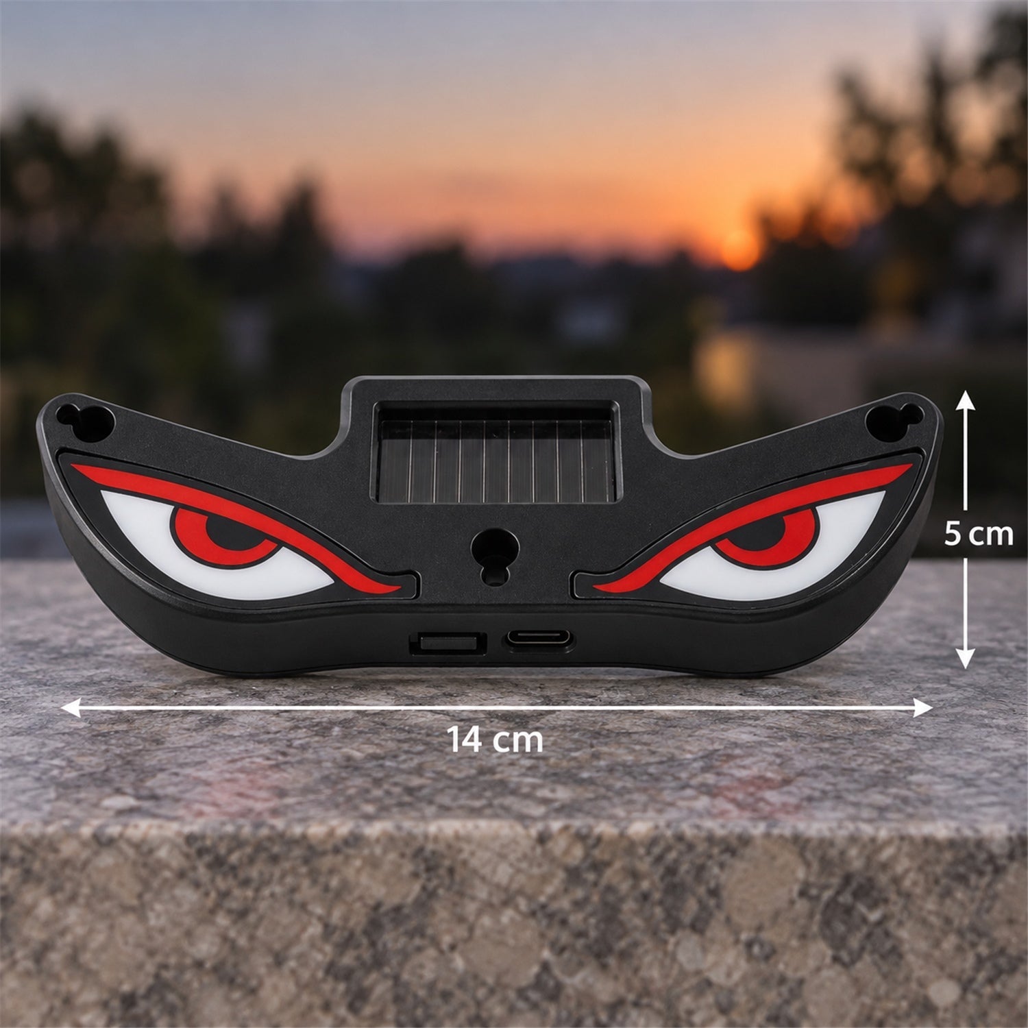 Black evil eye light with red and white eyes and a solar panel, displaying dimensions of 14 cm wide and 5 cm tall.