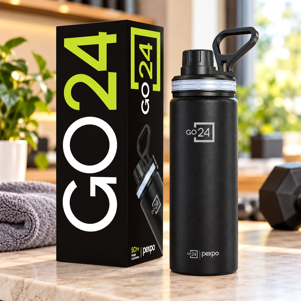 Black stainless steel bottle with a carry handle next to its product packaging on a kitchen counter.