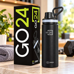Black stainless steel bottle with a carry handle next to its product packaging on a kitchen counter.