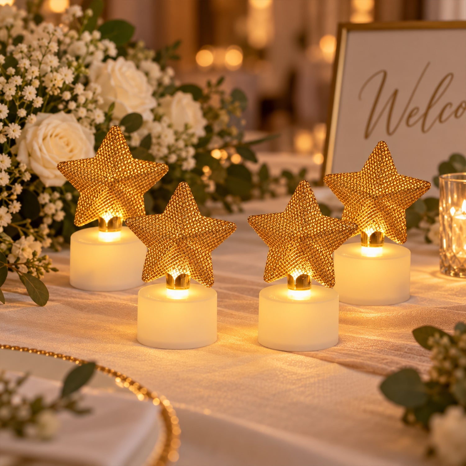 Four golden mesh star LED candles illuminate a formal table setting, surrounded by white floral arrangements.