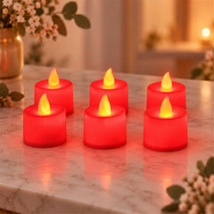 Six red flameless LED tealight candles with yellow glow arranged on a marble surface with flowers.
