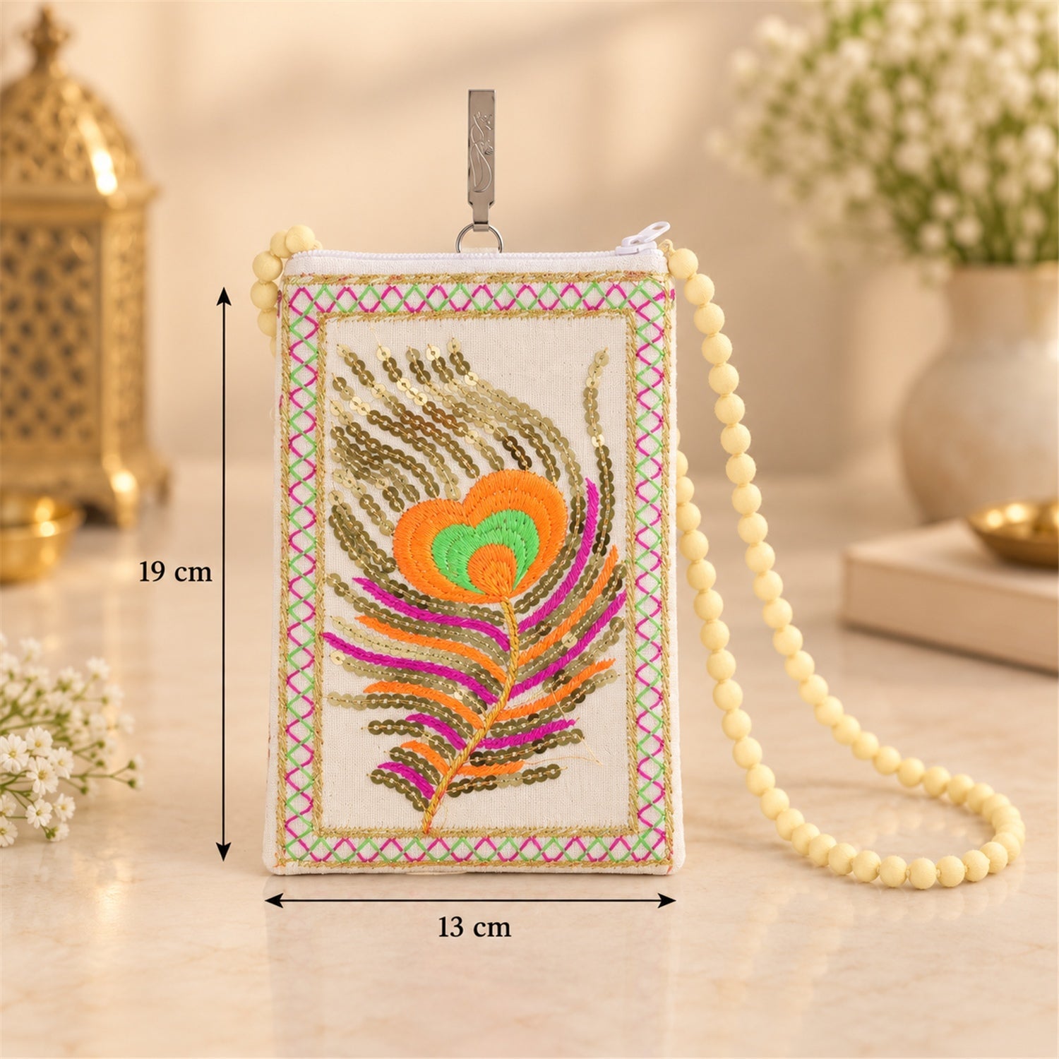 A cream mobile phone pouch with a colourful peacock feather design and yellow beaded strap, showing dimensions of 19x13 cm.